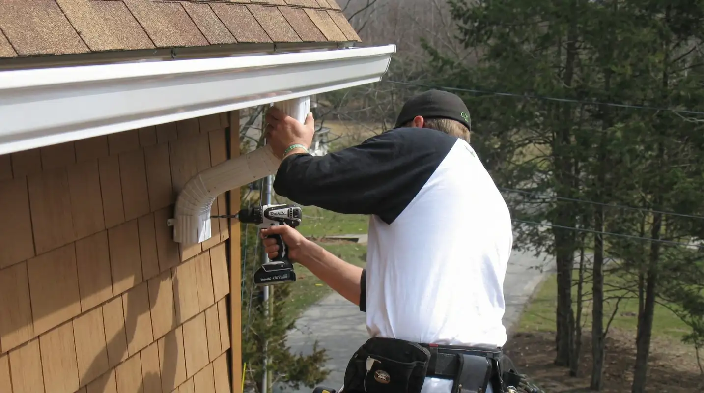 Professional contractor installing tan vinyl siding panels on a residential home exterior in Cedar Rapids, IA